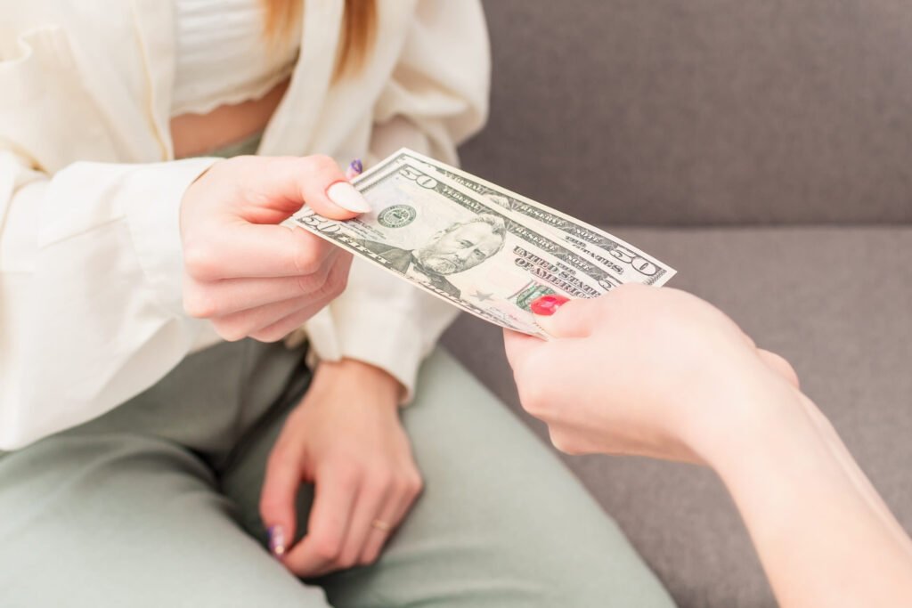 female hand is giving money to young woman at work, close up. business concept.
