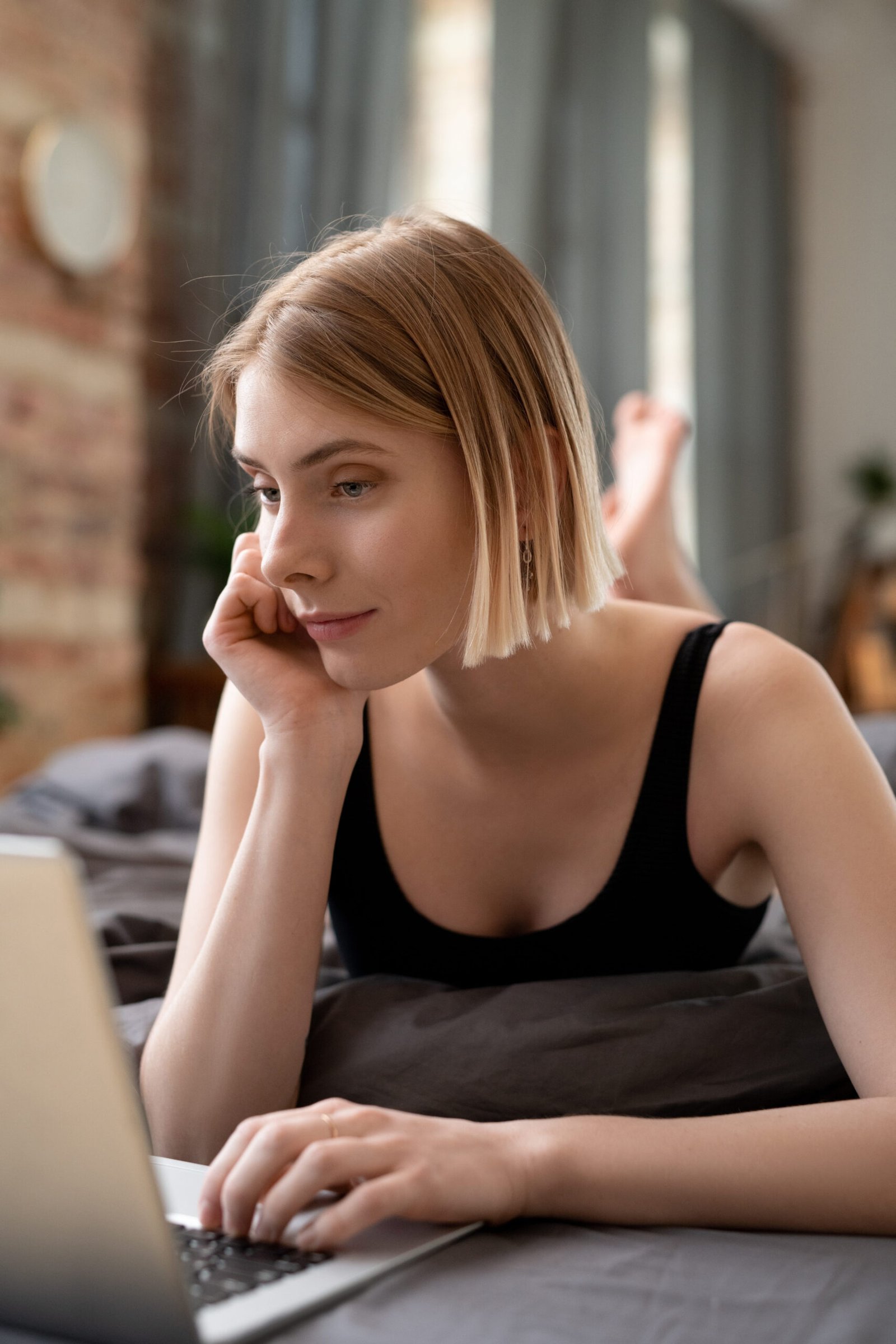 Is Therapy Really Too Expensive? Here's What's Actually Costing You young blonde girl lying on the bed and using laptop in her work in the room