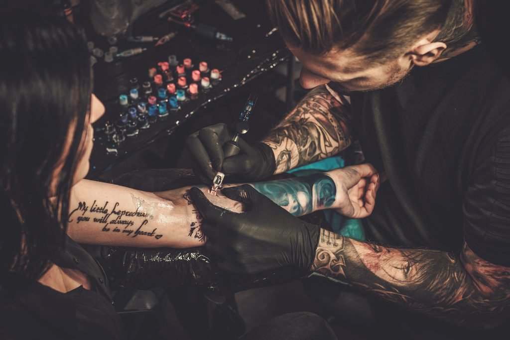 Mental Health Awareness Tattoos: Expressing Your Journey professional tattoo artist makes a tattoo on a young girl's hand.